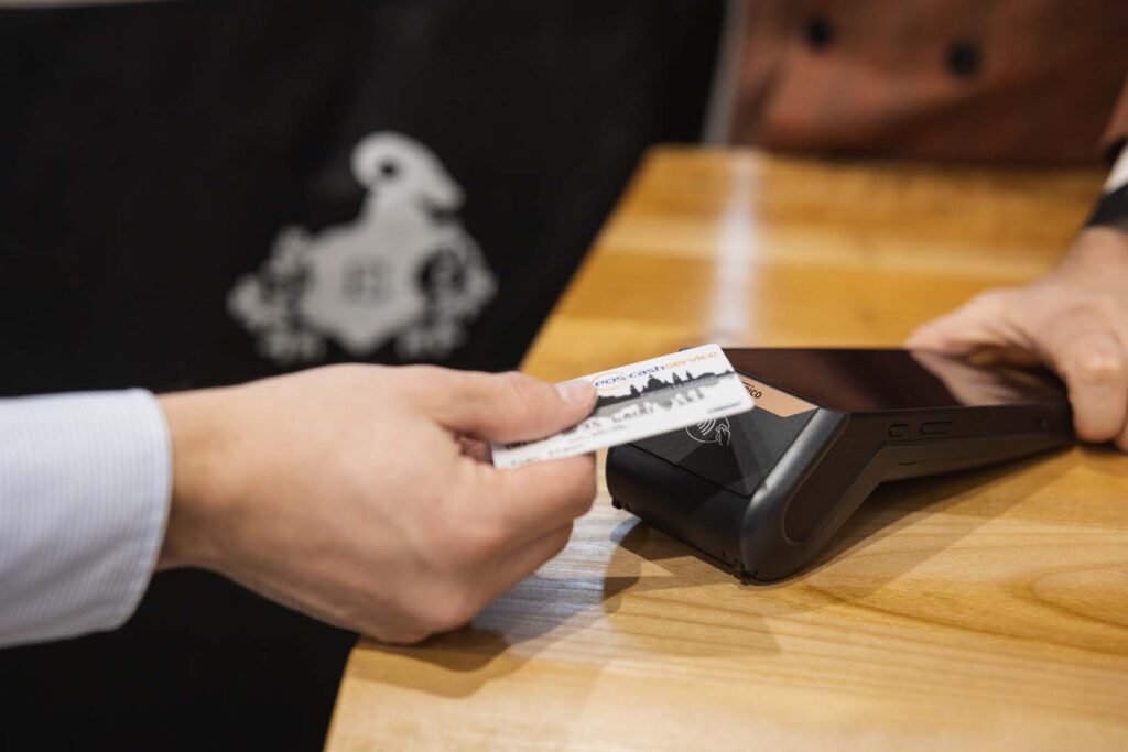 Girokarte wird kontaktlos an EC-Terminal gehalten – schnelle und bargeldlose Zahlungslösung mit POS-cashservice im stationären Handel