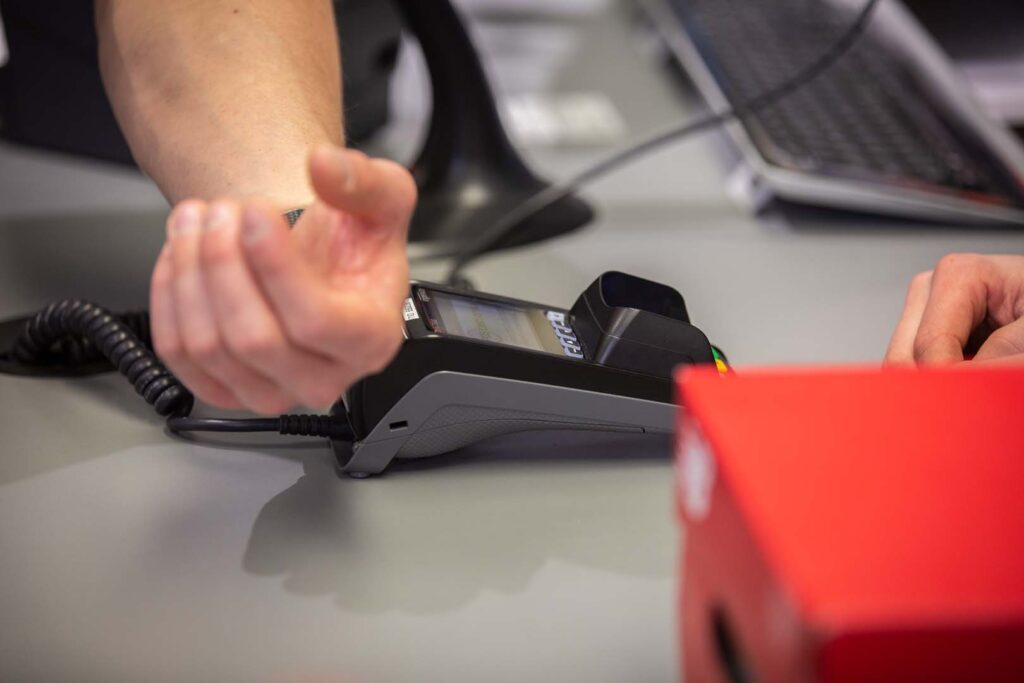 Kunde bereitet kontaktlose Zahlung an stationärem EC-Terminal vor – POS-cashservice unterstützt moderne Bezahlmethoden wie Smartwatch und Wearables