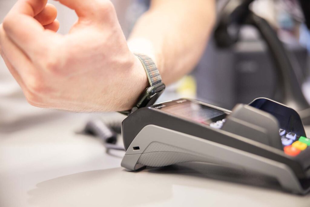 Kunde hält Smartwatch an EC-Terminal zur kontaktlosen Zahlung – POS-cashservice bietet NFC-fähige Zahlungslösungen für moderne Kundenanforderungen