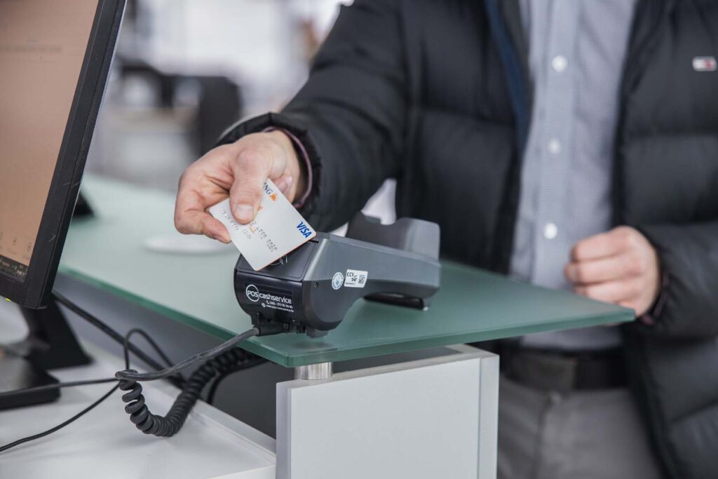 Kunde zahlt mit Girokarte am Empfangstresen über ein stationäres EC-Terminal – POS-cashservice bietet zuverlässige Zahlungslösungen für Büros, Praxen und Autohäuser