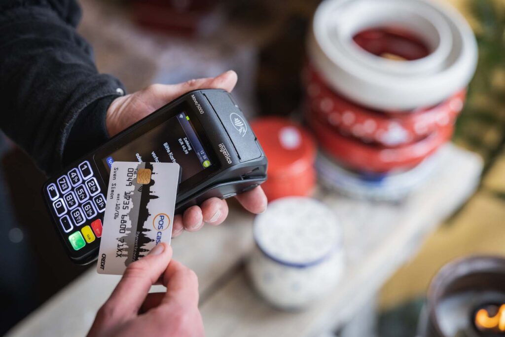 Kunde hält EC-Karte an mobiles Kartenterminal auf dem Weihnachtsmarkt – POS-cashservice ermöglicht einfache und kontaktlose Zahlungen für mobile Verkaufsstände