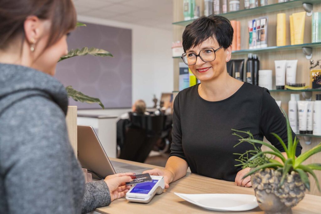 Kundin zahlt kontaktlos mit Smartphone im Friseursalon – POS-cashservice bietet das CCV A920 als modernes EC-Terminal für Beauty-, Wellness- und Dienstleistungsbetriebe