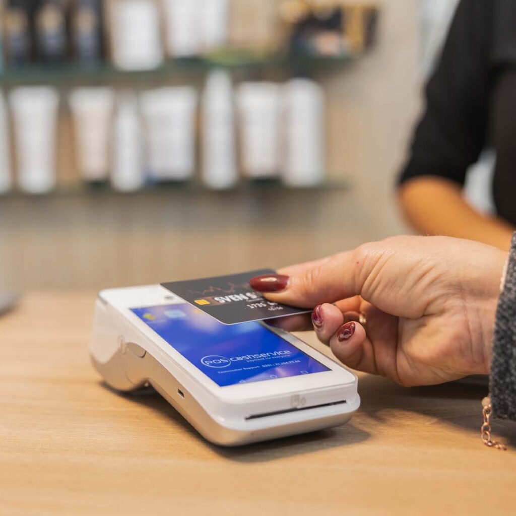 Kundin hält Kreditkarte an das CCV A920 Kartenterminal – POS-cashservice ermöglicht kontaktloses Bezahlen mit modernen Android-Terminals im Geschäft